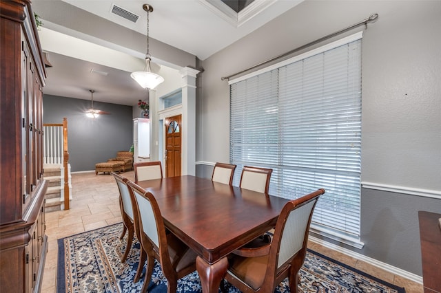 dining space featuring stone tile flooring, baseboards, visible vents, decorative columns, and stairway
