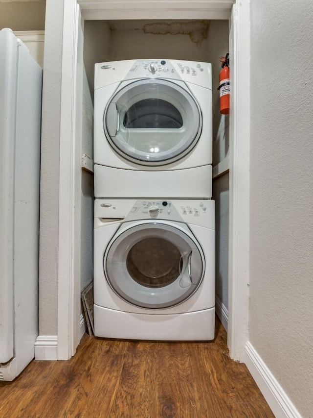 5550 Spring Valley Rd Unit F12, Dallas, TX 75254 - laundry area featuring estacked washer and dryer, wood finished floors, and baseboards