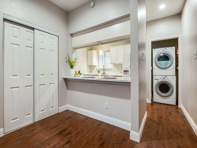 5550 Spring Valley Rd Unit F12, Dallas, TX 75254 - laundry area featuring stacked washing machine and dryer, dark wood finished floors, and baseboards