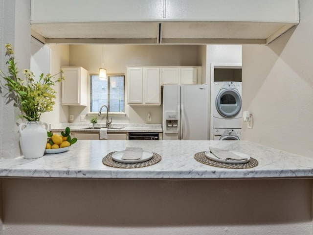 5550 Spring Valley Rd Unit F12, Dallas, TX 75254 - kitchen featuring a sink, white fridge with ice dispenser, stacked washer and clothes dryer, white cabinetry, and light stone counters