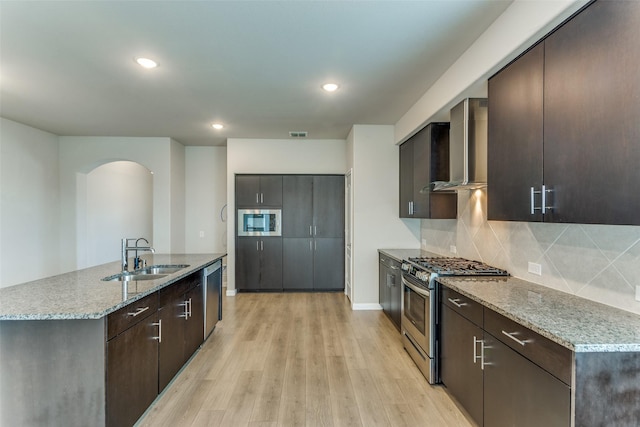 4444 Pentridge Dr, Fort Worth, TX 76036 - kitchen with a sink, stainless steel appliances, wall chimney range hood, light wood finished floors, and arched walkways
