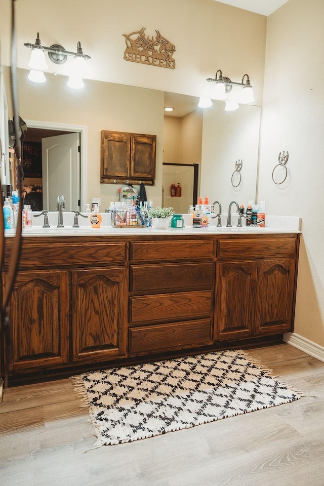 710 Mockingbird St, Bonham, TX 75418 - full bathroom with baseboards, double vanity, a sink, and wood finished floors
