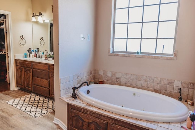 710 Mockingbird St, Bonham, TX 75418 - bathroom with a walk in closet, wood finished floors, vanity, and a jetted tub