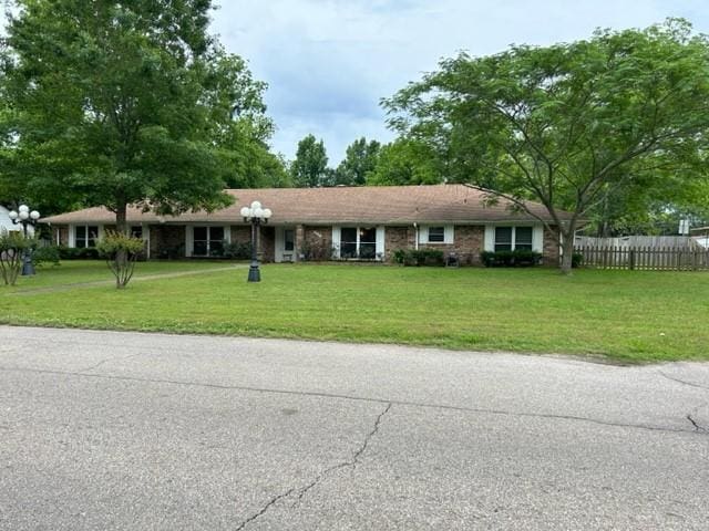 ranch-style house with fence and a front lawn
