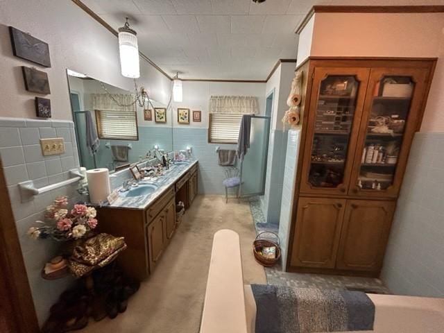 bathroom featuring a stall shower, tile walls, vanity, and wainscoting