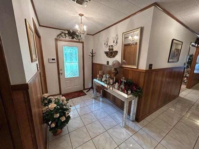 entrance foyer featuring wainscoting, crown molding, and an inviting chandelier