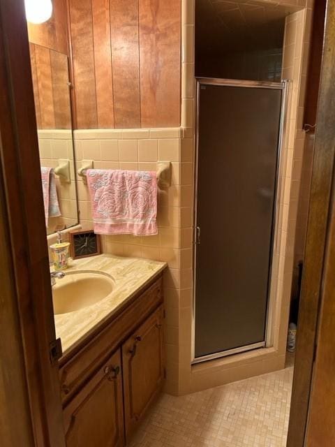 bathroom featuring vanity, tile walls, and a shower stall