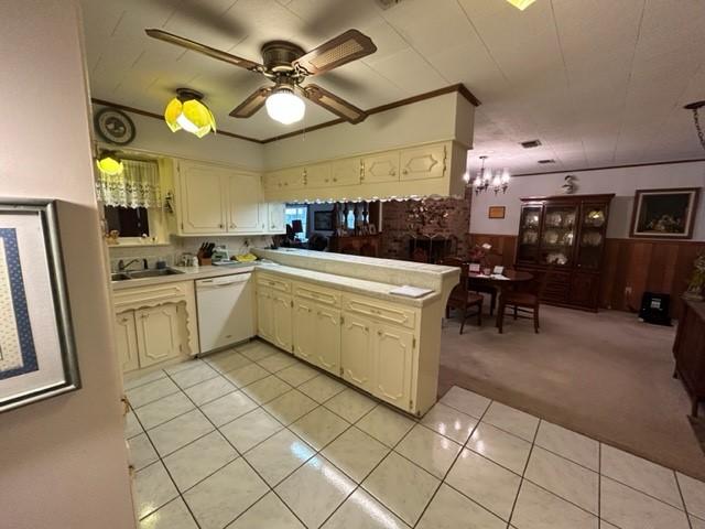 kitchen with light tile patterned floors, cream cabinetry, wainscoting, light countertops, and white dishwasher