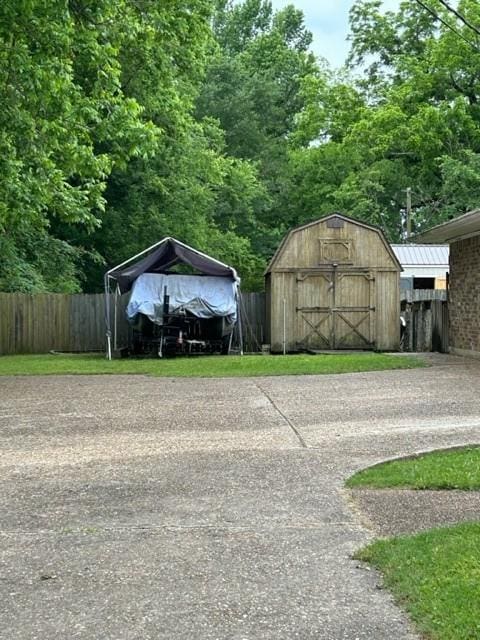 view of shed with driveway, fence, and a carport