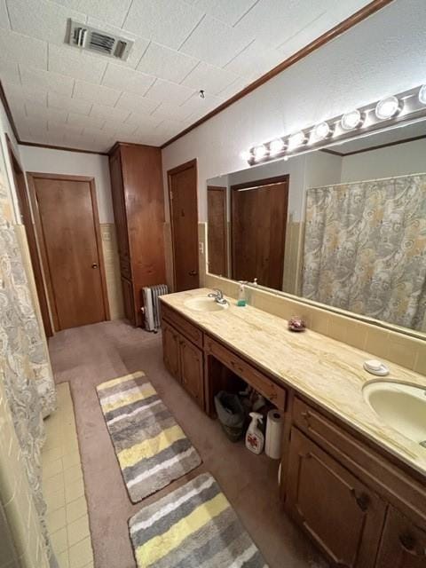 full bathroom featuring crown molding, radiator heating unit, visible vents, and double vanity