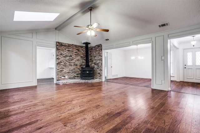 2 Preston Trail Ct, Pantego, TX 76013 - unfurnished living room featuring wood finished floors, a ceiling fan, lofted ceiling with skylight, visible vents, and a wood stove