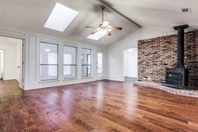 2 Preston Trail Ct, Pantego, TX 76013 - unfurnished living room with a ceiling fan, lofted ceiling with skylight, visible vents, wood finished floors, and a wood stove