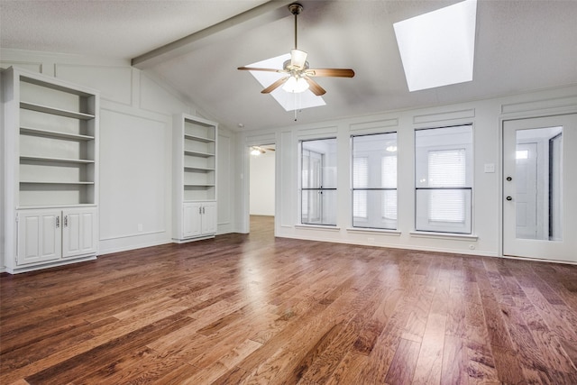 2 Preston Trail Ct, Pantego, TX 76013 - unfurnished living room with a decorative wall, vaulted ceiling with skylight, wood finished floors, built in shelves, and a ceiling fan
