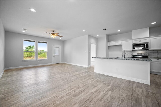 121 County Road 3471, Paradise, TX 76073 - kitchen with dark stone countertops, stainless steel appliances, baseboards, ceiling fan, and backsplash