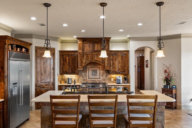kitchen featuring stainless steel built in fridge, visible vents, crown molding, arched walkways, and tasteful backsplash