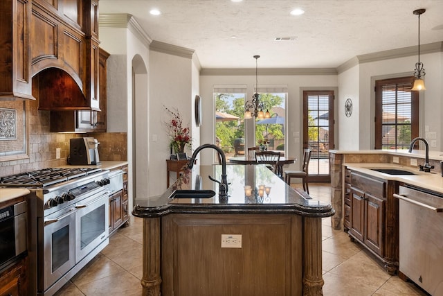 kitchen with a kitchen island with sink, appliances with stainless steel finishes, decorative backsplash, and a sink