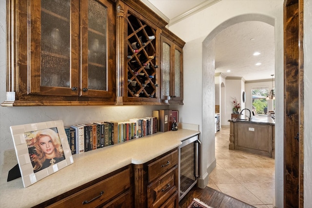 bar featuring crown molding, light tile patterned floors, arched walkways, and wine cooler