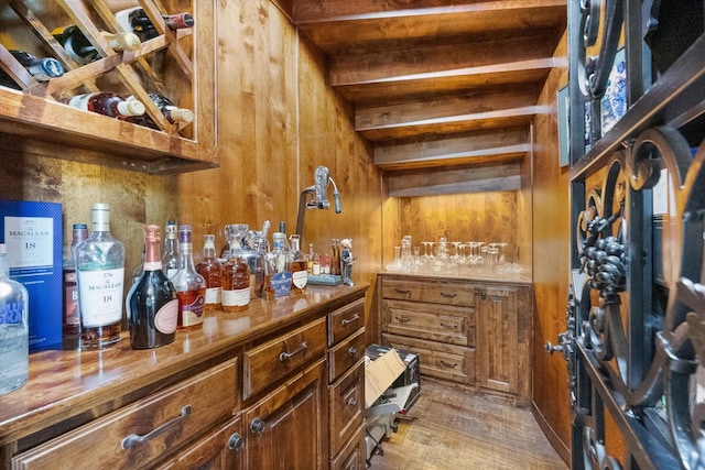 wine cellar with a bar, wooden walls, and wood finished floors