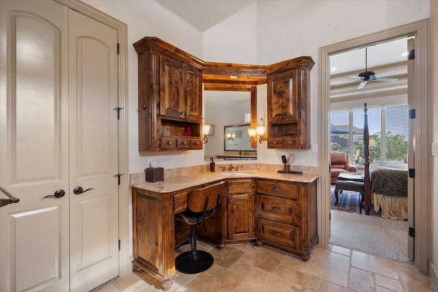 kitchen with a sink, stone tile floors, light countertops, and a ceiling fan