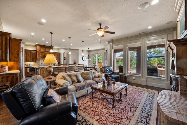 living area featuring dark wood-style flooring, a ceiling fan, ornamental molding, and recessed lighting