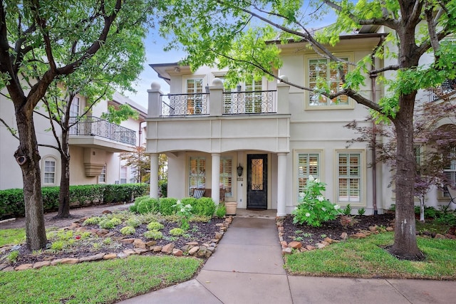 mediterranean / spanish home with a porch, stucco siding, and a balcony