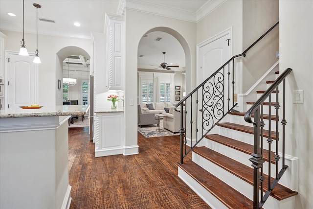 entrance foyer featuring ornamental molding, arched walkways, a ceiling fan, and visible vents