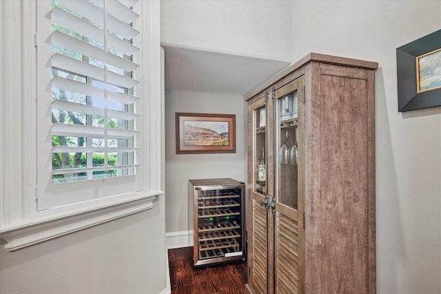 bar featuring beverage cooler, dark wood finished floors, and baseboards