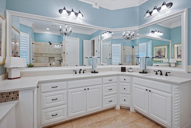 bathroom featuring ornamental molding, a notable chandelier, a tile shower, and a sink