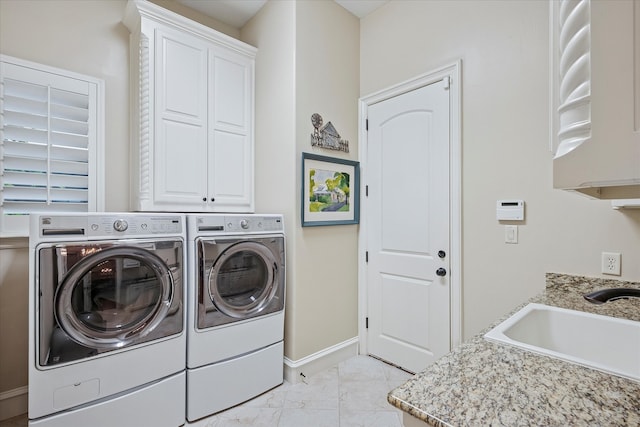 laundry area with a sink, separate washer and dryer, cabinet space, and baseboards