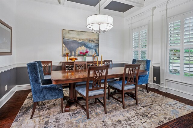 dining space with wood finished floors, ornamental molding, beamed ceiling, coffered ceiling, and a notable chandelier