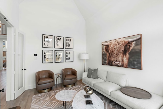 living area with wood finished floors, high vaulted ceiling, and baseboards
