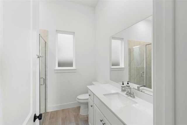 bathroom with a stall shower, baseboards, vanity, toilet, and wood finished floors