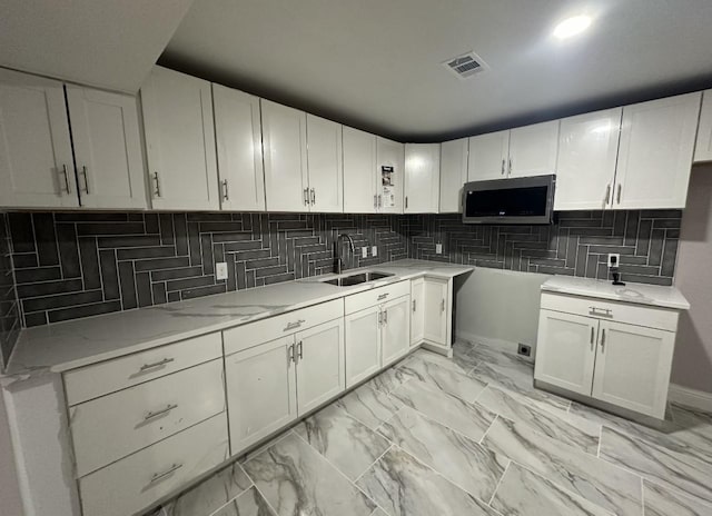 414 Ussery, Bowie, TX 76230 - kitchen featuring a sink, visible vents, stainless steel microwave, decorative backsplash, and light stone counters