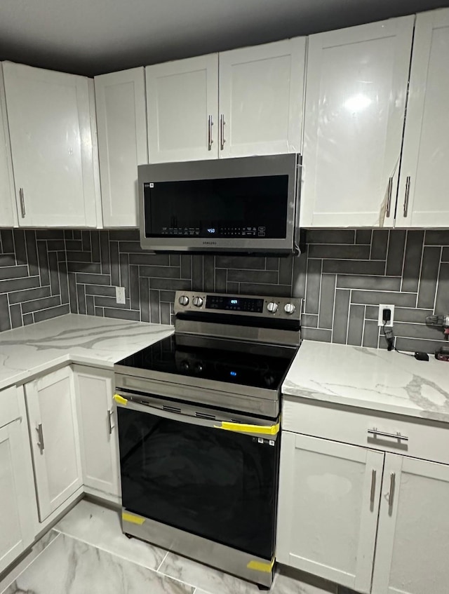 414 Ussery, Bowie, TX 76230 - kitchen featuring appliances with stainless steel finishes, decorative backsplash, light stone counters, and white cabinetry