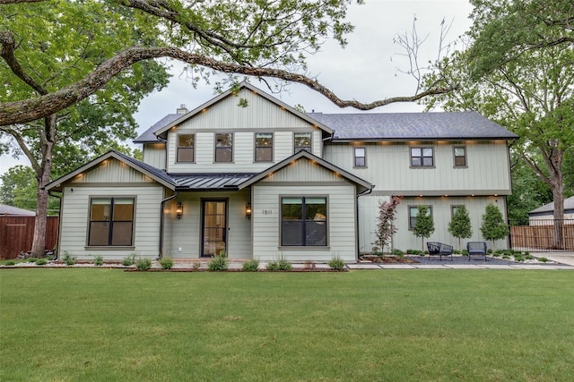 modern farmhouse style home featuring metal roof, fence, a front yard, and a standing seam roof