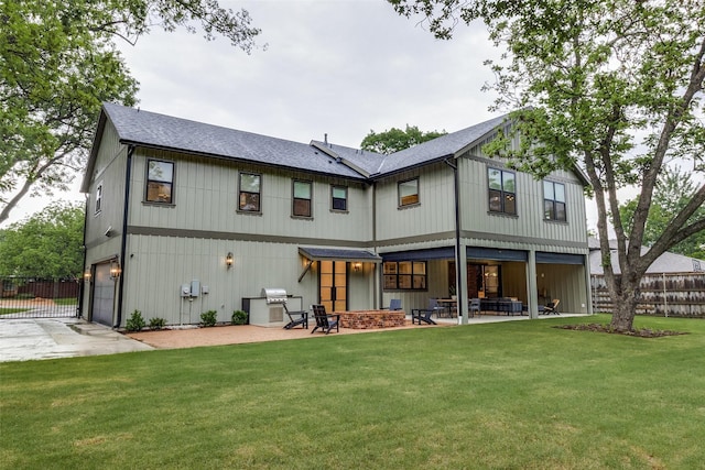 back of property featuring a yard, fence, an attached garage, and a patio area