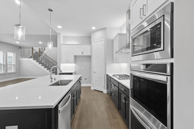 13101 Scissortail Dr, Frisco, TX 75035 - kitchen with stainless steel appliances, a sink, white cabinets, wood finished floors, and pendant lighting