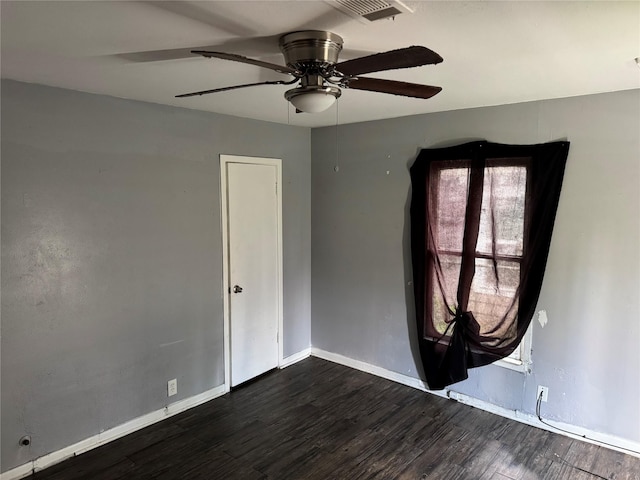 spare room with baseboards, dark wood-style floors, a ceiling fan, and visible vents