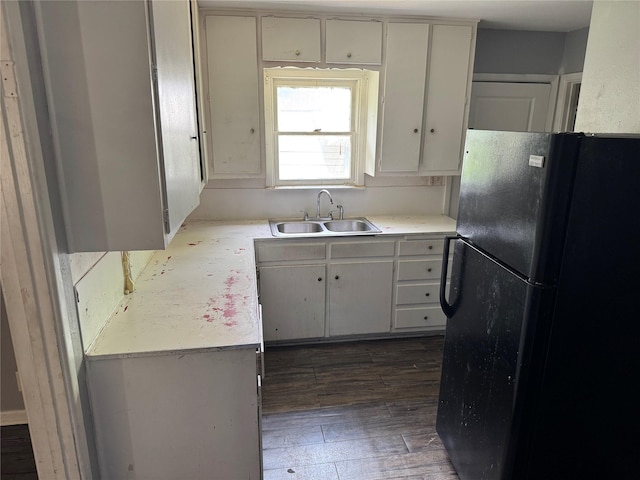 kitchen featuring a sink, freestanding refrigerator, dark wood-style flooring, and light countertops