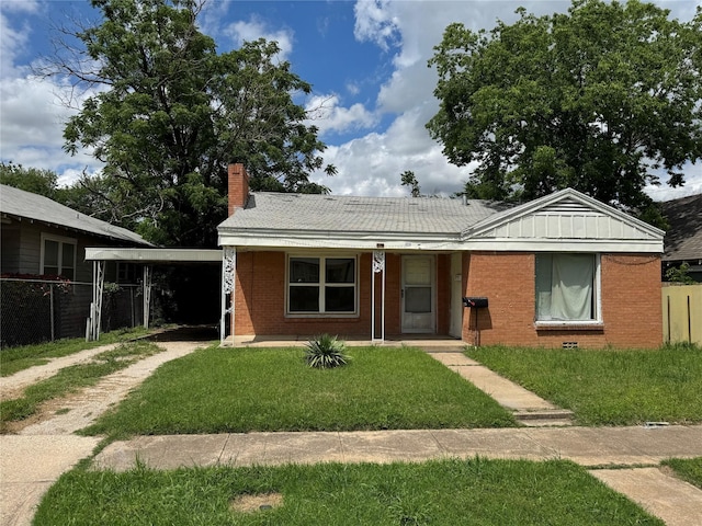 view of front facade with covered porch, a chimney, a front lawn, brick siding, and driveway
