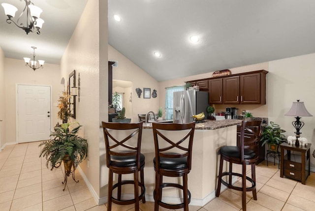 6113 Tilapia Dr, Fort Worth, TX 76179 - kitchen featuring stainless steel refrigerator with ice dispenser, a chandelier, a kitchen breakfast bar, light tile patterned floors, and dark brown cabinets