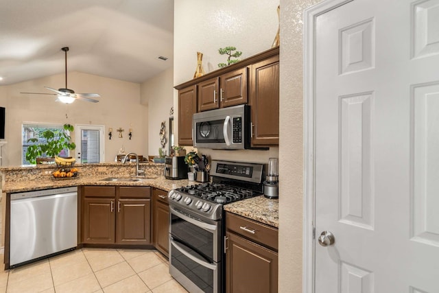 6113 Tilapia Dr, Fort Worth, TX 76179 - kitchen with stainless steel appliances, a sink, light tile patterned floors, vaulted ceiling, and a peninsula