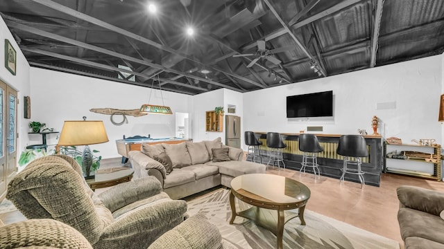 living room with ceiling fan, a bar, finished concrete floors, and billiards