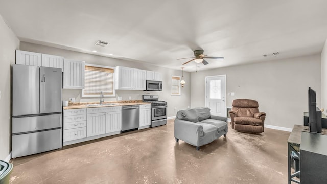 kitchen featuring concrete floors, a sink, stainless steel appliances, visible vents, and baseboards