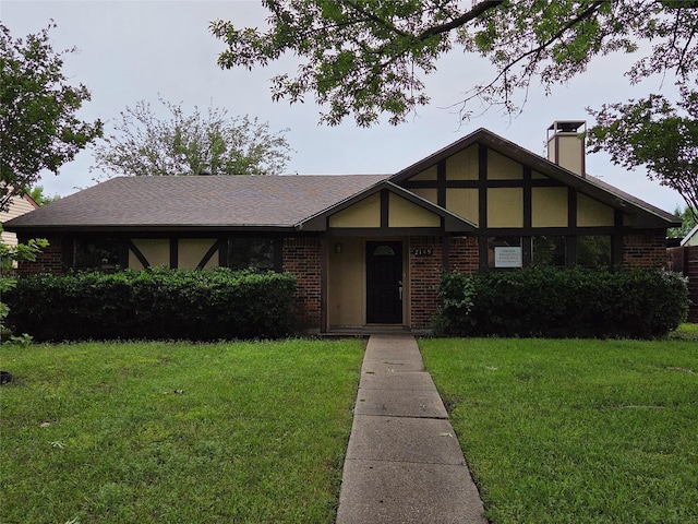 2149 Pueblo Dr, Garland, TX 75040 - tudor-style house with a front lawn, a chimney, and brick siding