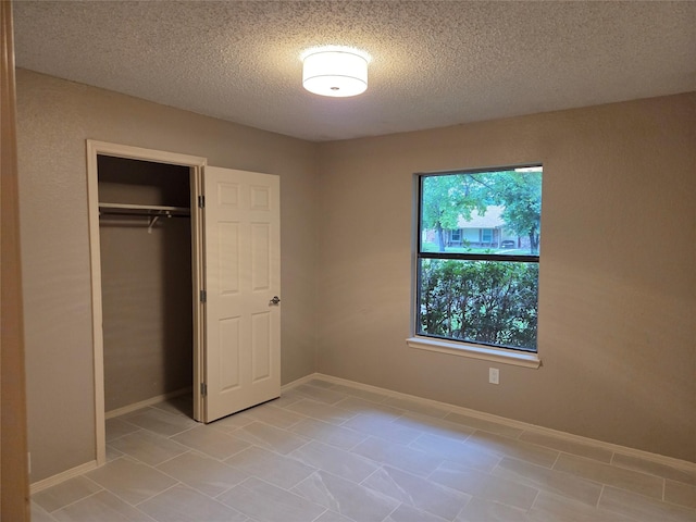 2149 Pueblo Dr, Garland, TX 75040 - unfurnished bedroom with a closet, a textured ceiling, baseboards, and light tile patterned floors