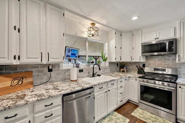 1601 E Bankhead Dr, Weatherford, TX 76086 - kitchen featuring stainless steel appliances, a sink, white cabinets, dark wood finished floors, and tasteful backsplash