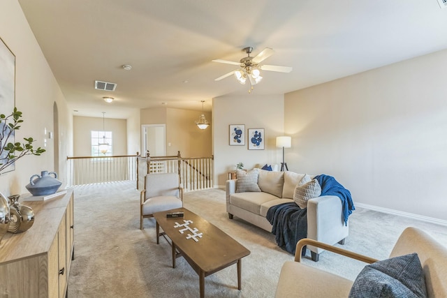 living area featuring light carpet, a ceiling fan, and baseboards