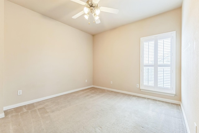 spare room featuring light colored carpet, baseboards, and a ceiling fan