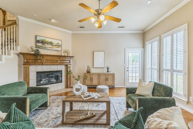 living area with crown molding, ceiling fan, stairs, baseboards, and light wood-type flooring